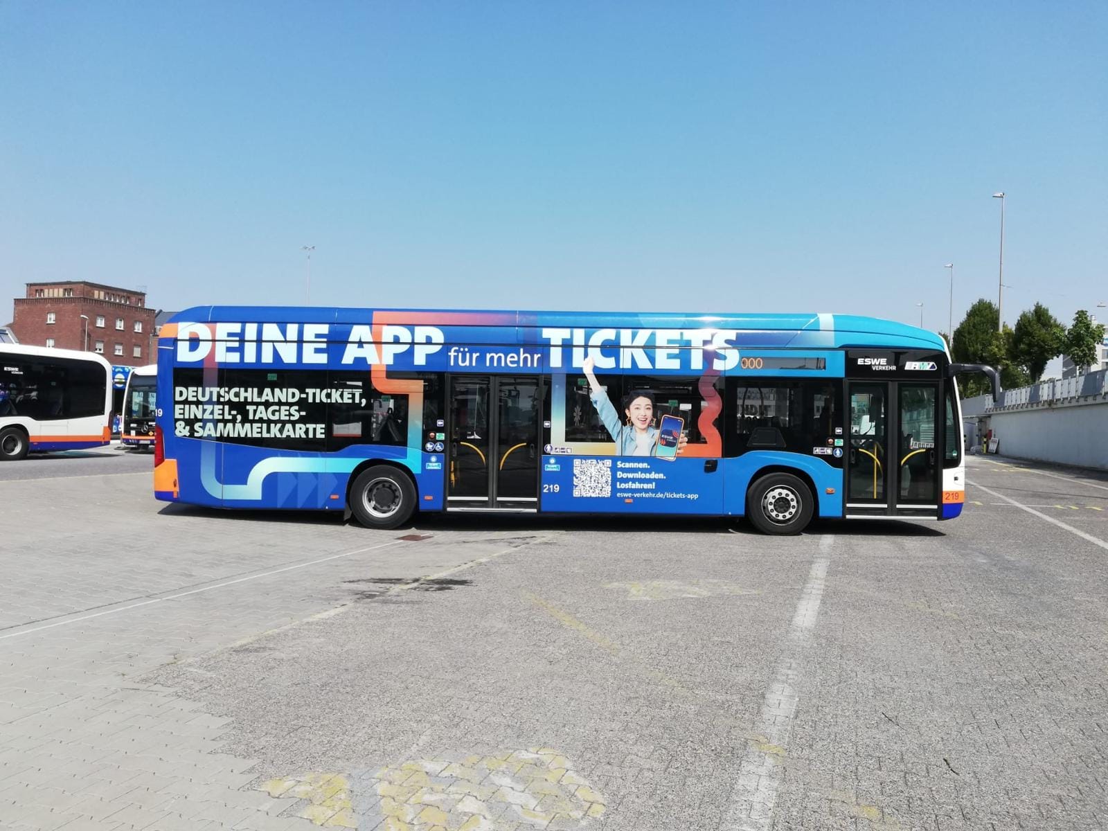Blauer Linienbus von ESWE Verkehr mit vollflächiger Werbung „Deine App für mehr Tickets“ auf der Seite
